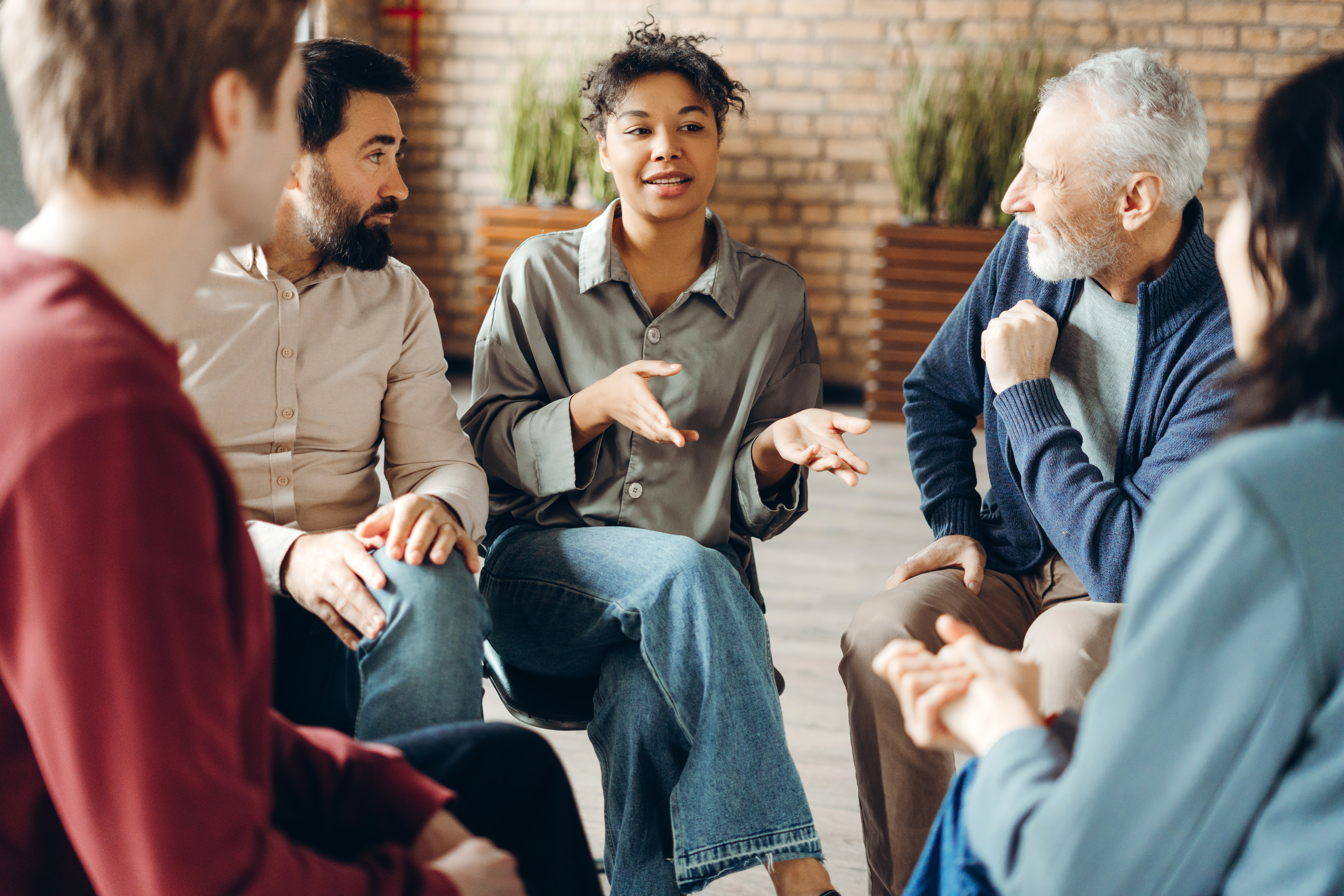 Several people are practicing NonViolent communication, sitting in a group
